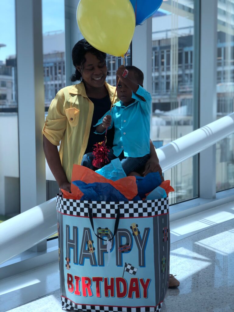 heart gift sponsor posing for a birthday celebration with his present and a balloon